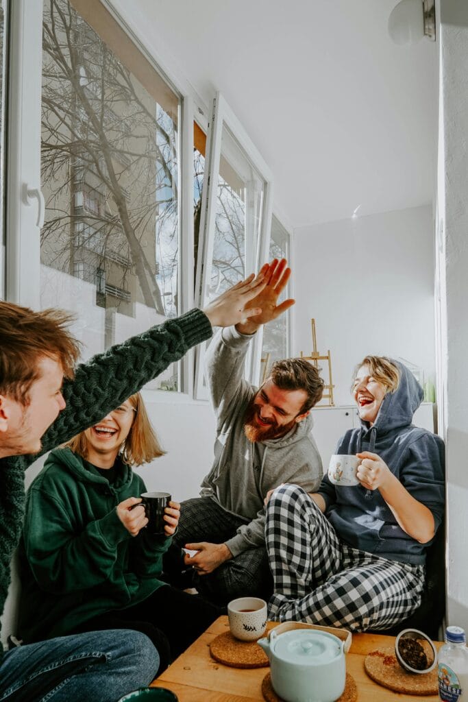 Friends laughing together indoors representing co-regulation and emotional connection | The CBT Center NJ